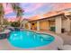 Inviting pool with waterfall feature, complemented by covered patio and outdoor seating under a colorful sunset sky at 5941 S Cambridge St, Chandler, AZ 85249
