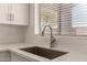 Modern kitchen with white cabinets, stainless steel sink, and bright natural light from the window at 10212 E Caballero St, Mesa, AZ 85207
