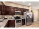 Contemporary kitchen with dark wood cabinets, stainless steel appliances, and granite countertops at 1836 N 77Th Gln, Phoenix, AZ 85035