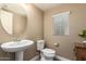Bright powder room with a pedestal sink, toilet, and natural light from a window at 1836 N 77Th Gln, Phoenix, AZ 85035