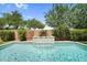 Inviting backyard pool featuring a stacked stone waterfall, surrounded by lush landscaping and a tiled border at 21352 E Domingo Rd, Queen Creek, AZ 85142