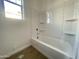 Bathroom with a white tub, shower combo with white vinyl walls; a window is to the left of the shower at 22669 E Saddle Way, Queen Creek, AZ 85142