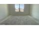 Unfinished bedroom with concrete flooring and a large window overlooking the front yard of the property at 22669 E Saddle Way, Queen Creek, AZ 85142