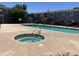 Community pool features a hot tub with a metal handrail in front of a building with a black metal fence at 2301 E University Dr # 269, Mesa, AZ 85213