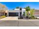 Modern home featuring a black garage door, front door with porch, and desert landscaping with a clear blue sky at 3038 E Stella Ln, Phoenix, AZ 85016