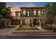 Charming two-story home features a cozy balcony, arched entryway, lush landscaping, and inviting curb appeal at 3042 N Beverly Pl, Buckeye, AZ 85396
