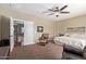 Carpeted main bedroom featuring an upstairs access door, ceiling fan, and cozy sitting area at 3177 S Sierra St, Gilbert, AZ 85295