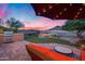 Outdoor living space with built in grill, fire pit and patio furniture under a lighted umbrella at sunset at 32359 N 129Th Dr, Peoria, AZ 85383