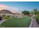 Serene backyard with a modern fire pit, artificial turf, lush landscaping, and breathtaking mountain backdrop for outdoor enjoyment at 32359 N 129Th Dr, Peoria, AZ 85383