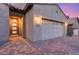 Charming exterior featuring a brick driveway, a two-car garage, a well-lit entry, and desert landscaping at 32359 N 129Th Dr, Peoria, AZ 85383