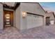 Charming exterior featuring a brick driveway, a two-car garage, a well-lit entry, and desert landscaping at 32359 N 129Th Dr, Peoria, AZ 85383