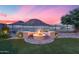 A backyard fire pit surrounded by built in benches, artificial turf, and desert landscaping at 32359 N 129Th Dr, Peoria, AZ 85383
