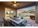 Charming covered patio featuring a ceiling fan, a dining table, and a view of the backyard with a fire pit and mountain views at 32359 N 129Th Dr, Peoria, AZ 85383