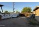View of the backyard with a trailer, discarded materials, and a white wall at 3946 W Holly St, Phoenix, AZ 85009