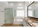 Bathroom with double sinks, granite countertops, soaking tub, and glass-enclosed shower at 4208 E Hamblin Dr, Phoenix, AZ 85050