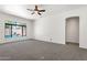 Spacious living room with carpeted floors, a ceiling fan, and a large window overlooking the outdoor pool area at 4208 E Hamblin Dr, Phoenix, AZ 85050