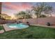Sparkling pool with waterfall feature surrounded by lush artificial grass and mature trees at sunset at 4208 E Hamblin Dr, Phoenix, AZ 85050