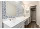 Bright bathroom featuring double sinks, patterned wall and a shower with glass door at 4722 W Via Cynthia --, Glendale, AZ 85301