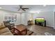 Open-concept living room with TV, neutral walls, wood floors, and plantation shutters at 520 S Greenfield Rd # 7, Mesa, AZ 85206