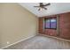 Bedroom featuring plush carpet, ceiling fan and a window with a brick wall at 5733 E Jaeger St, Mesa, AZ 85205