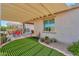 Well-maintained backyard with a covered patio, artificial turf, and decorative potted plants at 60 S Agua Fria Ln, Casa Grande, AZ 85194