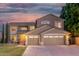 Inviting two-story home at dusk with a manicured lawn and three-car garage at 6961 W Honeysuckle Dr, Peoria, AZ 85383