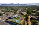 Expansive aerial view showcasing a home with a pool, tennis court, solar panels, and mountain backdrop at 8001 E Voltaire Ave, Scottsdale, AZ 85260