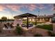 Backyard oasis with fire pit, outdoor seating and TV, spacious lawn, and a view of the pickleball court and solar panels at 8001 E Voltaire Ave, Scottsdale, AZ 85260