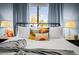Bright bedroom features a metal frame bed, layered throw pillows, blue curtains, and view of palm trees at 8001 E Voltaire Ave, Scottsdale, AZ 85260