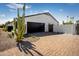 Detached garage with a modern black door and brick paved driveway enhanced by desert flora at 8001 E Voltaire Ave, Scottsdale, AZ 85260