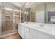 Bright bathroom featuring double sinks, tile floors, a large vanity, and glass shower at 13373 W Boca Raton Rd, Surprise, AZ 85379