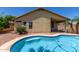 Backyard oasis featuring a sparkling pool, lush landscaping, and a covered patio at 13373 W Boca Raton Rd, Surprise, AZ 85379