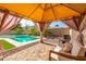 Relaxing backyard cabana featuring comfortable seating and a view of the sparkling pool at 13636 W Calavar Rd, Surprise, AZ 85379