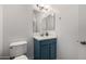 Cozy powder room with white toilet, vanity with blue cabinets, undermount sink, and brushed nickel faucet at 13636 W Calavar Rd, Surprise, AZ 85379