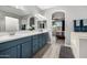 Bright bathroom featuring a double vanity with blue cabinets, white countertops, and an arched entry to the bedroom at 13636 W Calavar Rd, Surprise, AZ 85379