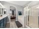 Bright bathroom featuring a glass shower, soaking tub, double vanity with blue cabinets, and an arched entry to the bedroom at 13636 W Calavar Rd, Surprise, AZ 85379