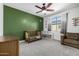 A well-lit carpeted bedroom with crib, reading nook, and ceiling fan at 13636 W Calavar Rd, Surprise, AZ 85379
