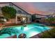 Backyard swimming pool with underwater lighting, manicured lawn, and mature palm trees at 13636 W Calavar Rd, Surprise, AZ 85379