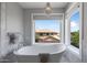 Bright bathroom featuring a free-standing tub, marble tile floor, and a decorative chandelier at 14609 S 24Th Way, Phoenix, AZ 85048