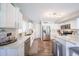 Open concept kitchen with stainless steel appliances, subway tile backsplash, white cabinetry, and wood-look floors at 14770 W Columbine Dr, Surprise, AZ 85379