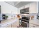 Clean kitchen featuring stainless steel appliances, white cabinets, and marble countertops at 14770 W Columbine Dr, Surprise, AZ 85379