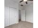 An empty bedroom with carpet, ceiling fan, closet, and white walls at 15674 W Mackenzie Dr, Goodyear, AZ 85395