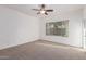 An airy bedroom features carpeted floors, a ceiling fan, and a large window for natural light at 15674 W Mackenzie Dr, Goodyear, AZ 85395