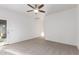 An airy bedroom features carpeted floors, a ceiling fan, and a glass door at 15674 W Mackenzie Dr, Goodyear, AZ 85395