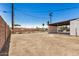 View of the backyard with a dirt lot, privacy fence, and a detached carport at 162 N Hunt W Dr, Mesa, AZ 85203