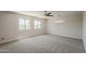 Expansive bedroom with neutral carpet, ceiling fan, and windows overlooking the neighborhood at 1671 E Silktassel Trl, San Tan Valley, AZ 85143