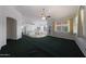 Bright open living room with views of the kitchen, large window, and dark green carpet at 19007 N 79Th Dr, Glendale, AZ 85308