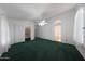Bright main bedroom showcasing a walk-in closet, ceiling fan, and dark green carpet at 19007 N 79Th Dr, Glendale, AZ 85308