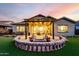 Stunning backyard featuring a covered patio, pavers, artificial grass, and a custom fire pit with seating at 21022 E Arroyo Verde Ct, Queen Creek, AZ 85142