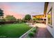 Expansive backyard with lush artificial turf, a custom fire pit area, and an inviting covered patio at 21022 E Arroyo Verde Ct, Queen Creek, AZ 85142